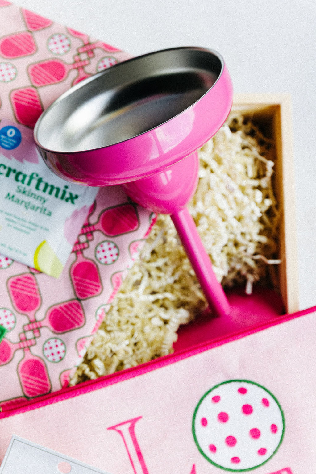 Close-up of pink margarita glass and pickleball towel with Craftmix margarita packet inside wooden gift box