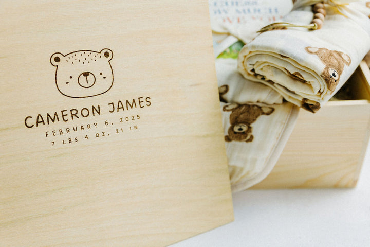 Wooden box with engraved baby details and a baby blanket with bear design.