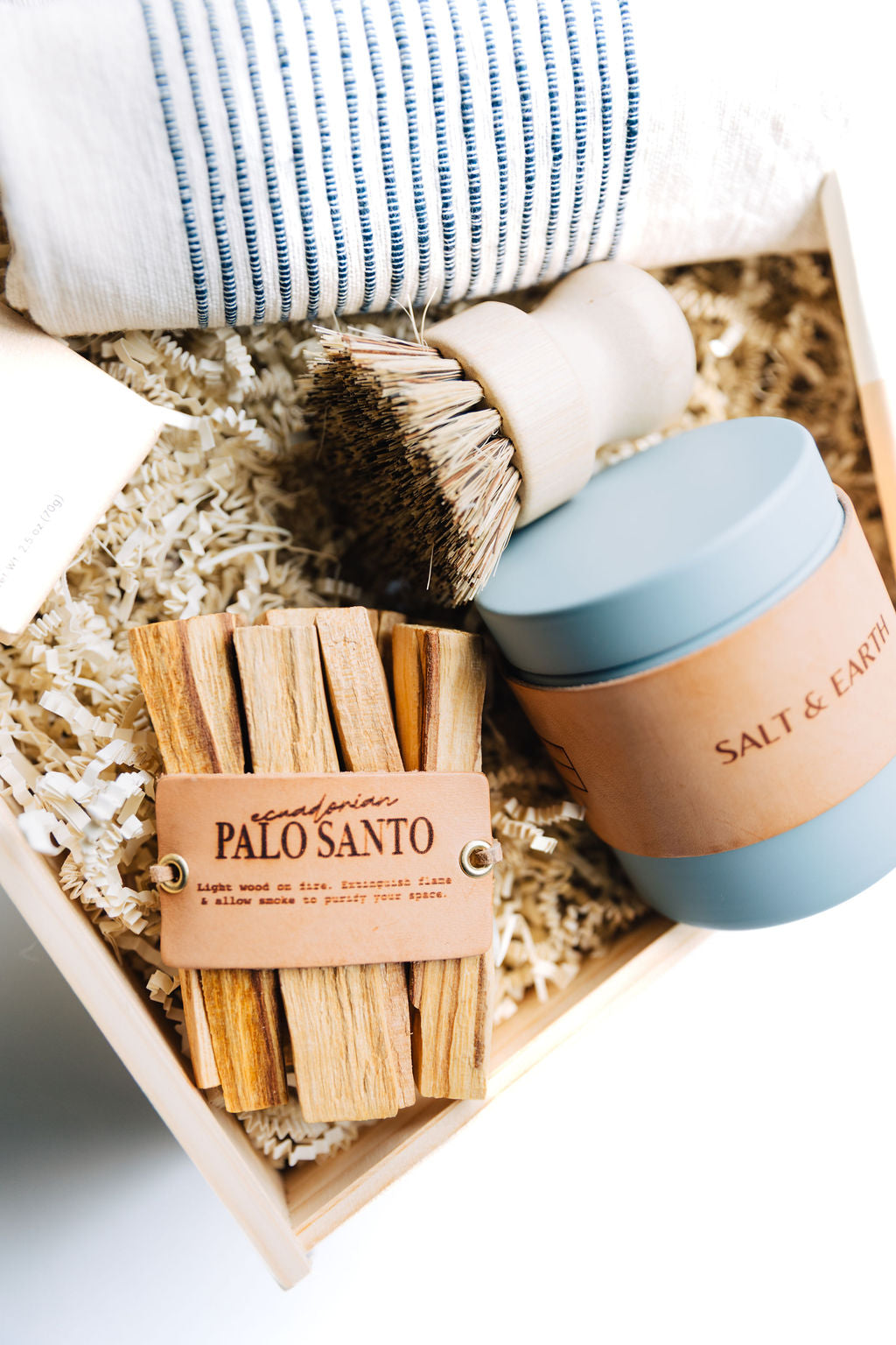 Palo Santo sticks, brush, and Salt & Earth candle in a wooden box.