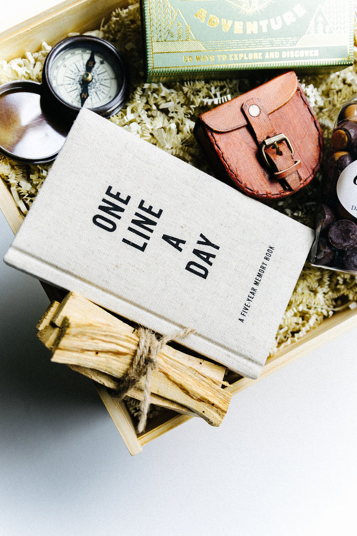 Close-up of One Line a Day linen journal and leather compass case in luxury Adventure Awaits gift box