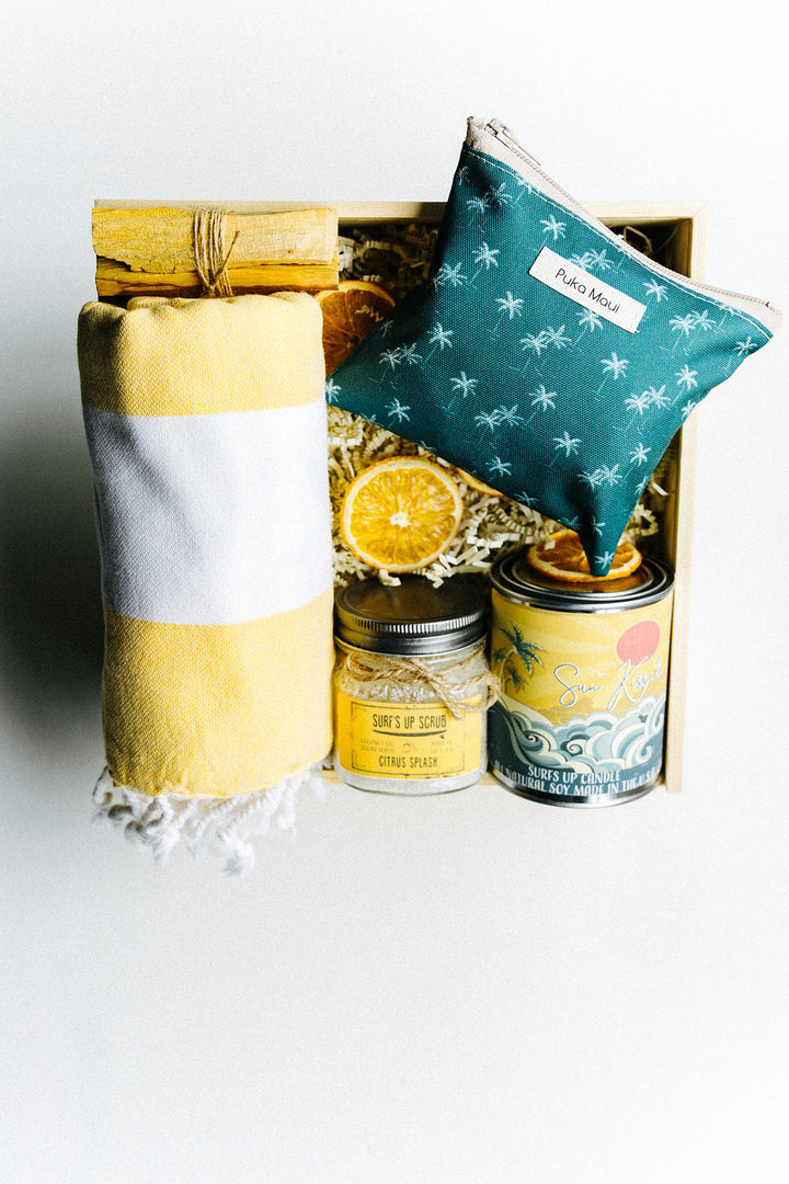 Top down view of Jupiter Beach Box contents including towel, green zippered pouch, candle, sugar scrub, and palo santo sticks
