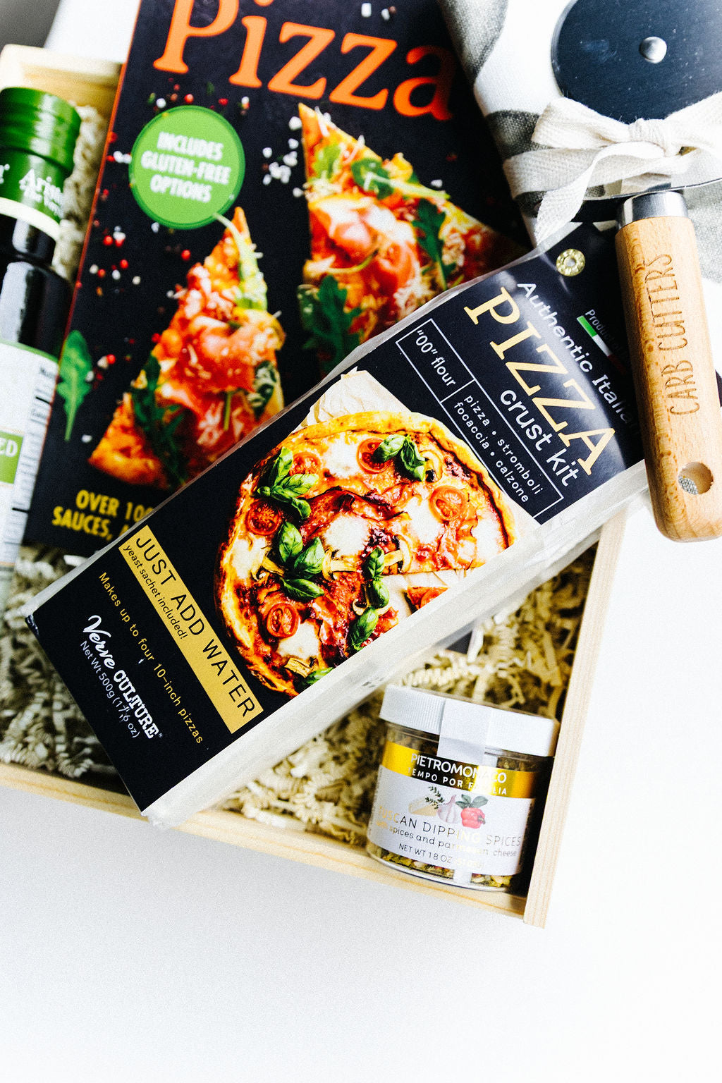 Close-up of pizza crust kit and pizza cutter in gift box – highlighting rustic wood handle with “Carb Cutters” engraving.