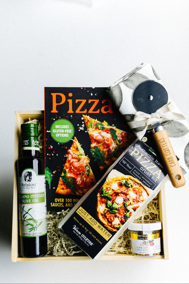Styled wooden gift box of Homemade Pizza Co. Gift Box – cookbook, pizza crust kit, olive oil, spices, tea towel, and pizza cutter nestled in crinkle paper filler