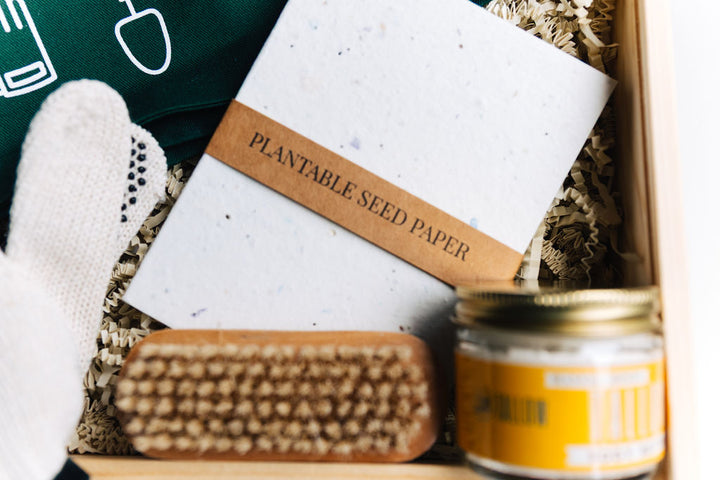 Plantable seed paper notebook next to nail brush and tallow body butter inside gift box