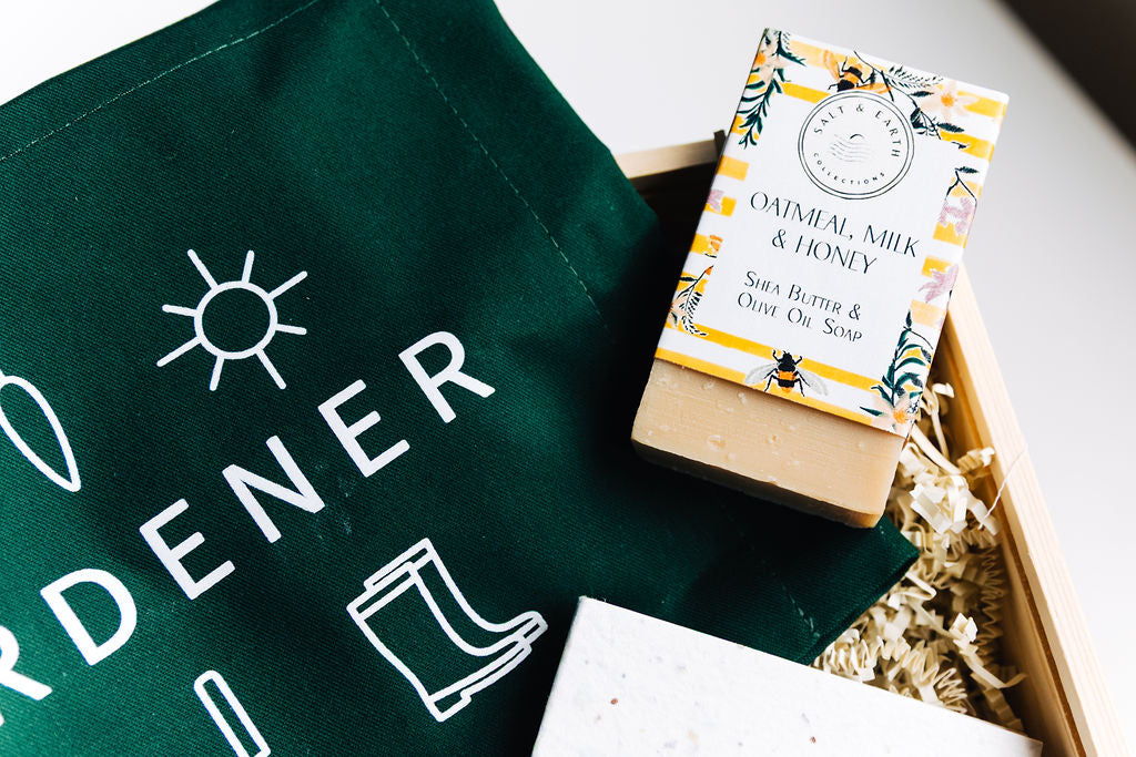 Oatmeal Milk & Honey soap resting on forest green gardener apron with white garden icon print