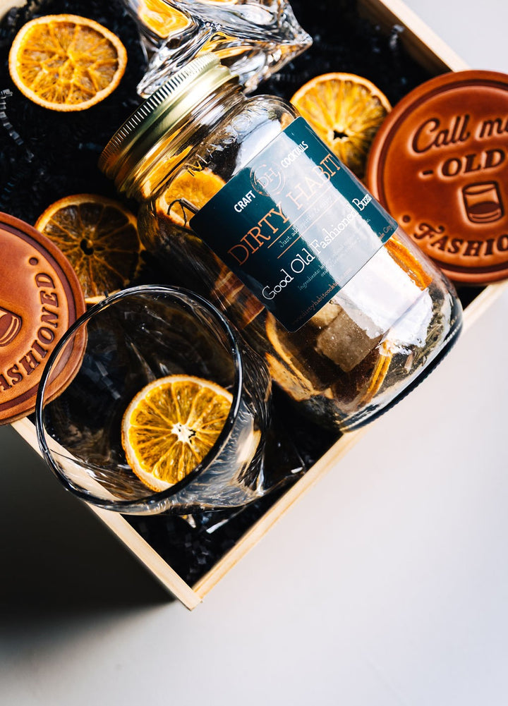 Detail shot of Call Me Old Fashioned leather coaster next to crystal whiskey glass and dried orange slice