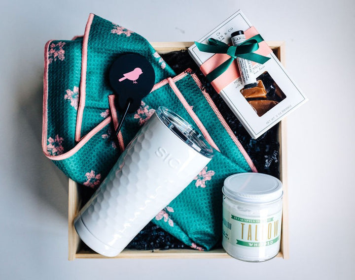 Fore Her women’s golf gift box with white dimpled tumbler, floral golf towel, whipped tallow moisturizer, lip balm, and mocha caramels