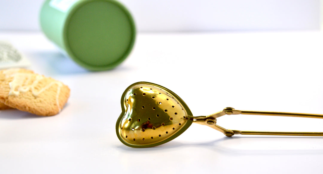 Heart-shaped gold loose leaf tea infuser on white background, included in Steeped in Stillness mindfulness gift box