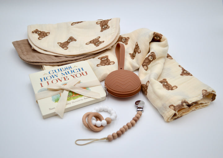 Flat lay of Welcome Little Bear Gift Box with swaddle, burp cloth, pacifier case, teether, and children’s book