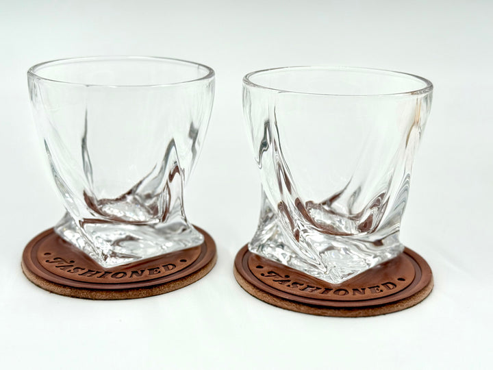 Pair of crystal twist whiskey glasses resting on Call Me Old Fashioned leather coasters – perfect groomsmen or whiskey gift set