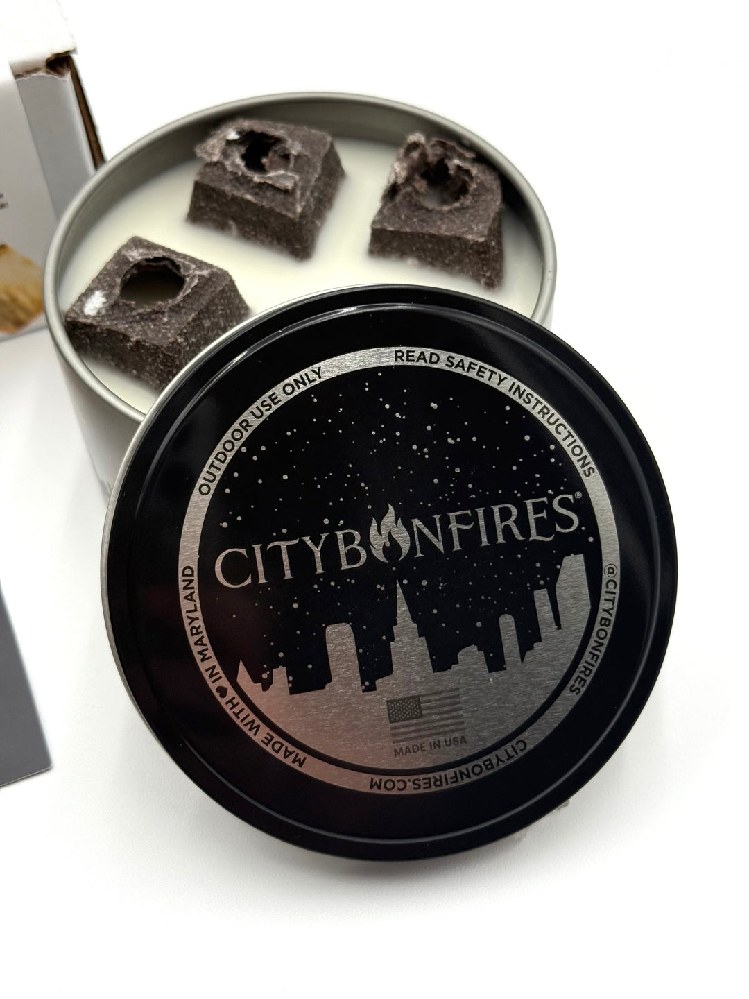 Open tin showing four fuel pods with black lid nearby, perfect for cozy outdoor fires
