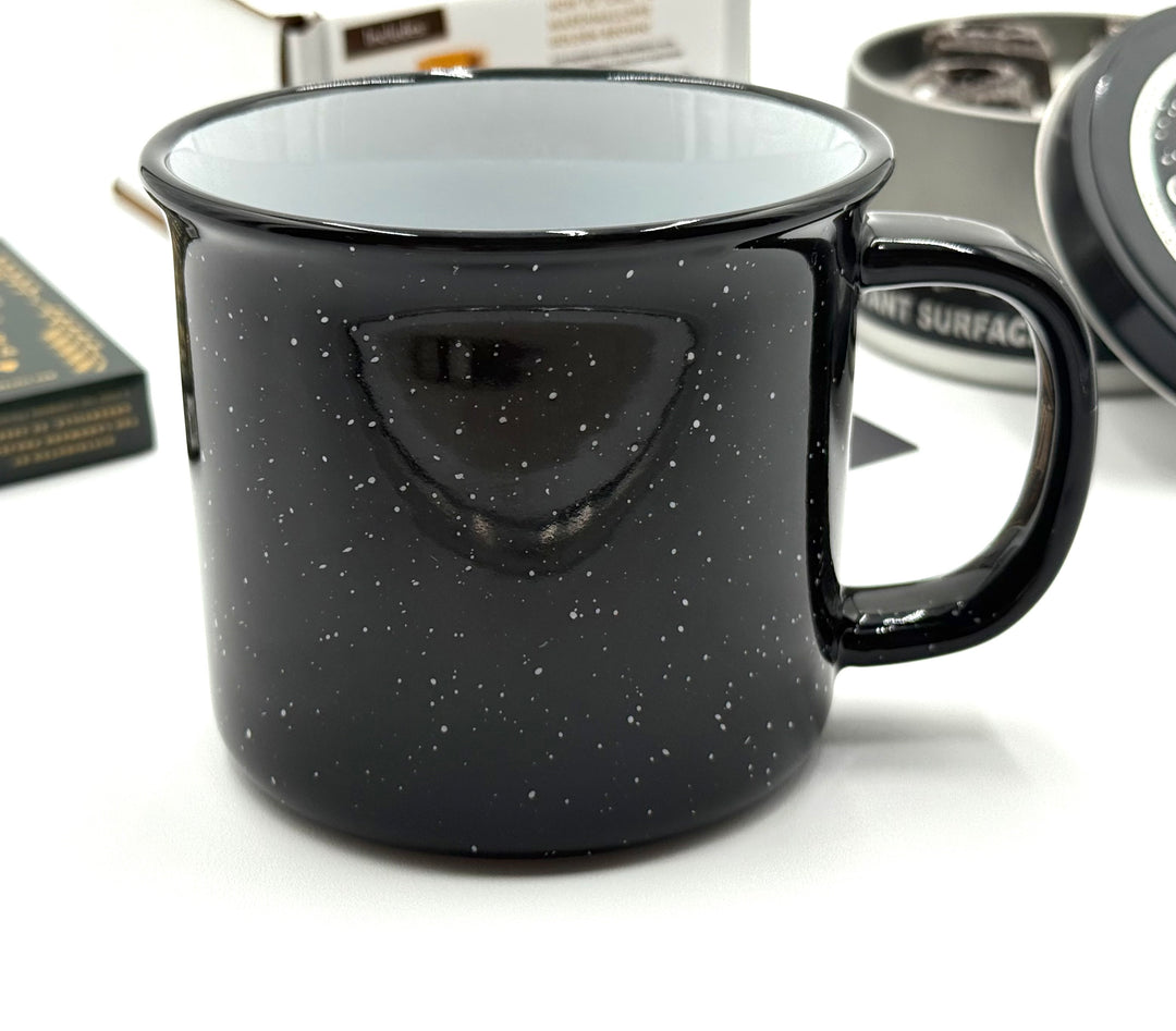 Classic enamel-style mug with white speckles, ideal for sipping hot drinks fireside