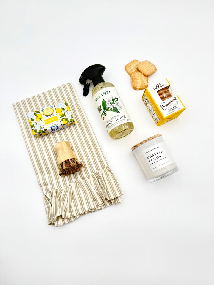 Flat lay of Home Sweet Home Gift Box contents – candle, cleaner, scrub brush, towel, cookies, and soap