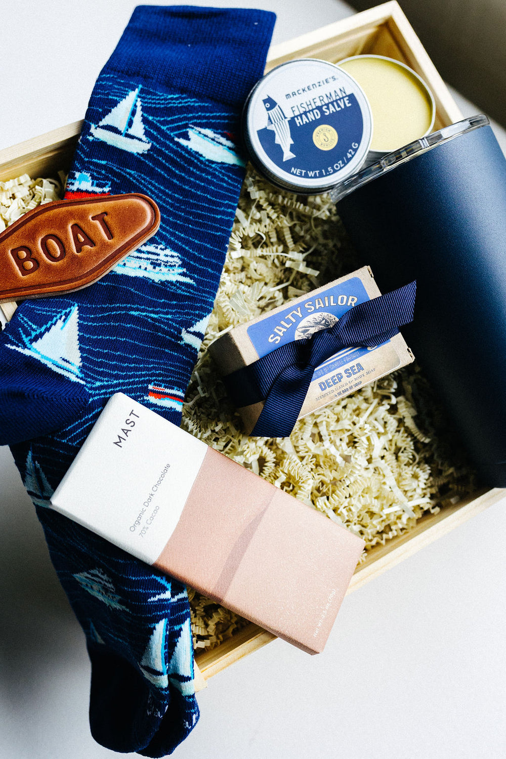 Angled view of Salty Sailor men’s nautical gift box with navy tumbler, socks, soap, keychain, and fisherman hand salve.