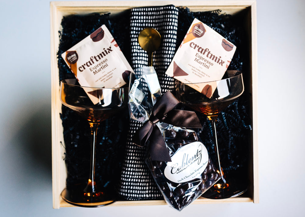 Golden Hour Gift Box styled with amber coupe glasses, napkins, bar spoon, and gourmet chocolates