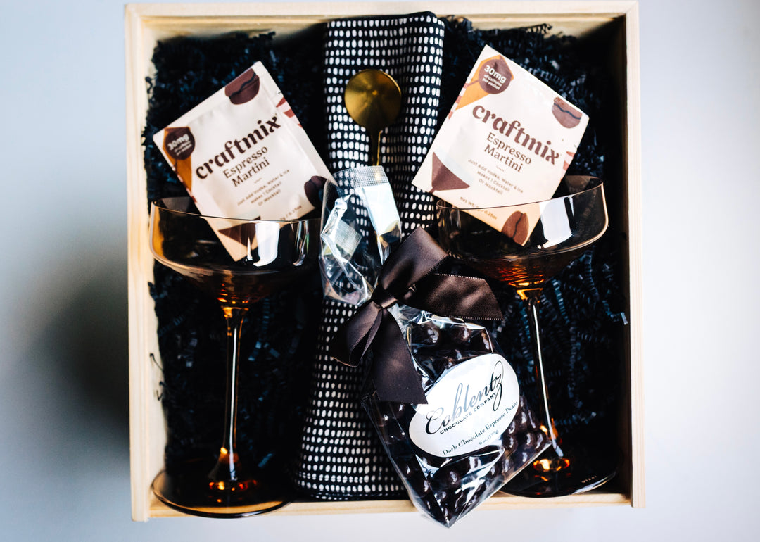 Golden Hour Gift Box styled with amber coupe glasses, napkins, bar spoon, and gourmet chocolates