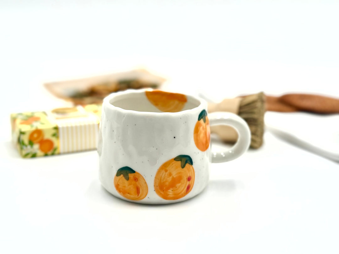 White mug with orange fruit design on a white background
